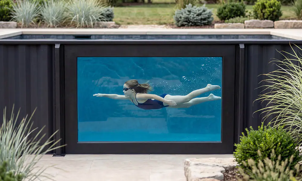 Girl swimming in container pool visible through acrylic window